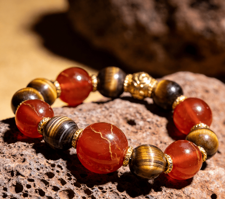 Aries warrior mala bracelet with tiger eye beads and red agate guru bead on volcanic rock slab