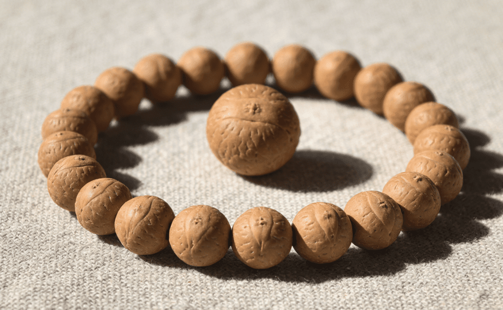 108 traditional mala beads with a large guru bead resting on linen cloth