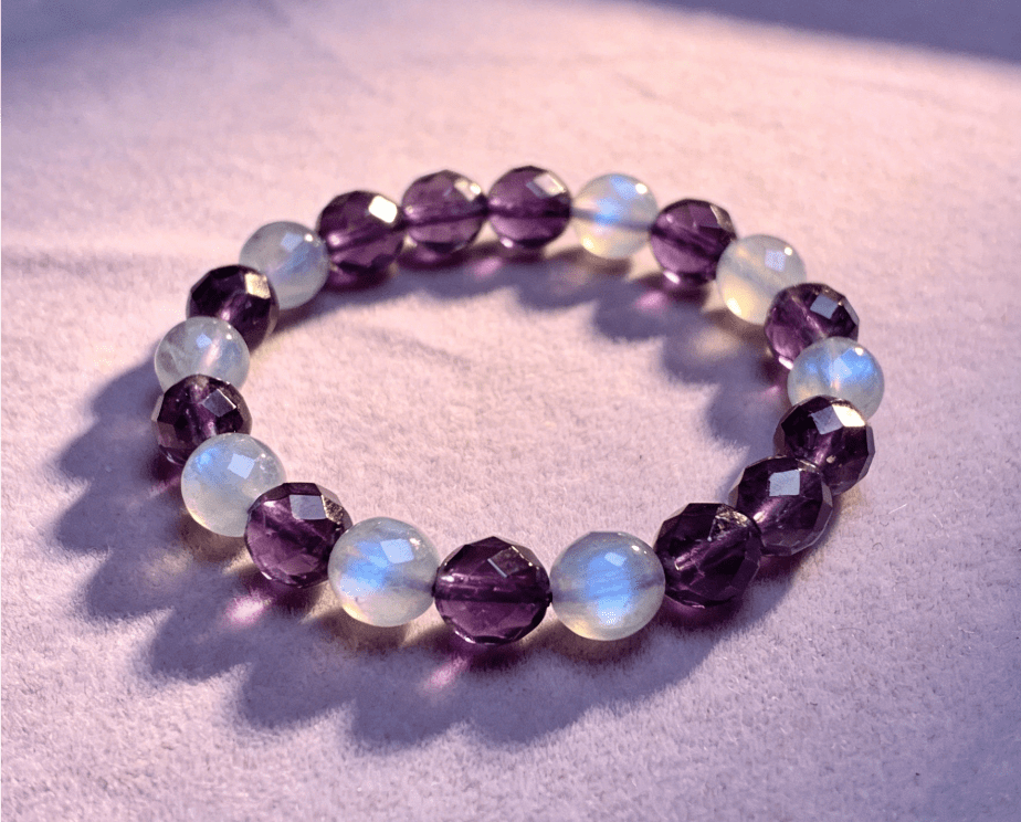 Pisces spiritual mala bracelet with amethyst and moonstone beads on pale purple linen cloth