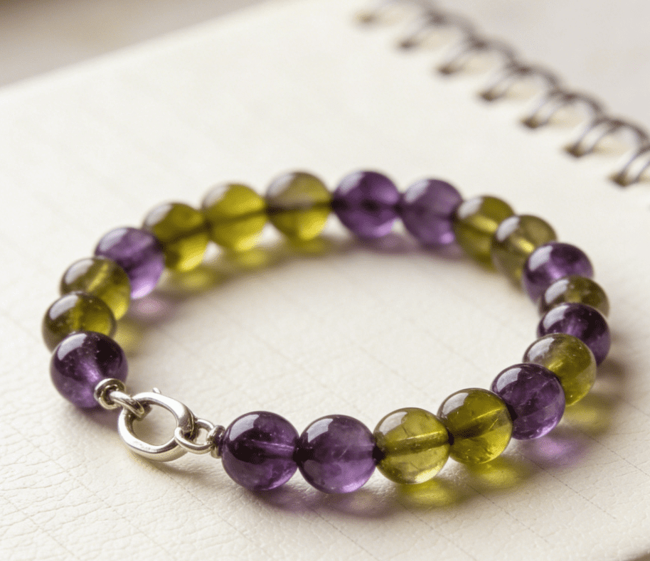 Virgo balanced mala bracelet with peridot and amethyst beads on off-white notebook