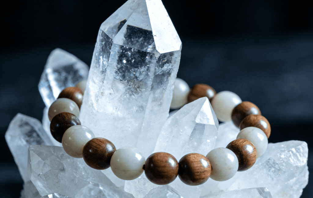 Mala bracelet cleansing under moonlight on a clear quartz cluster