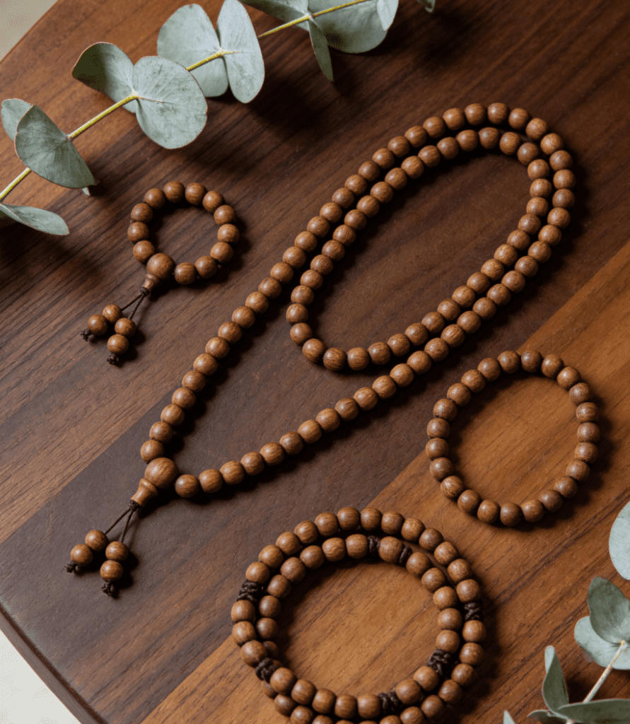 Three mala lengths arranged on a walnut wood table with eucalyptus leaves